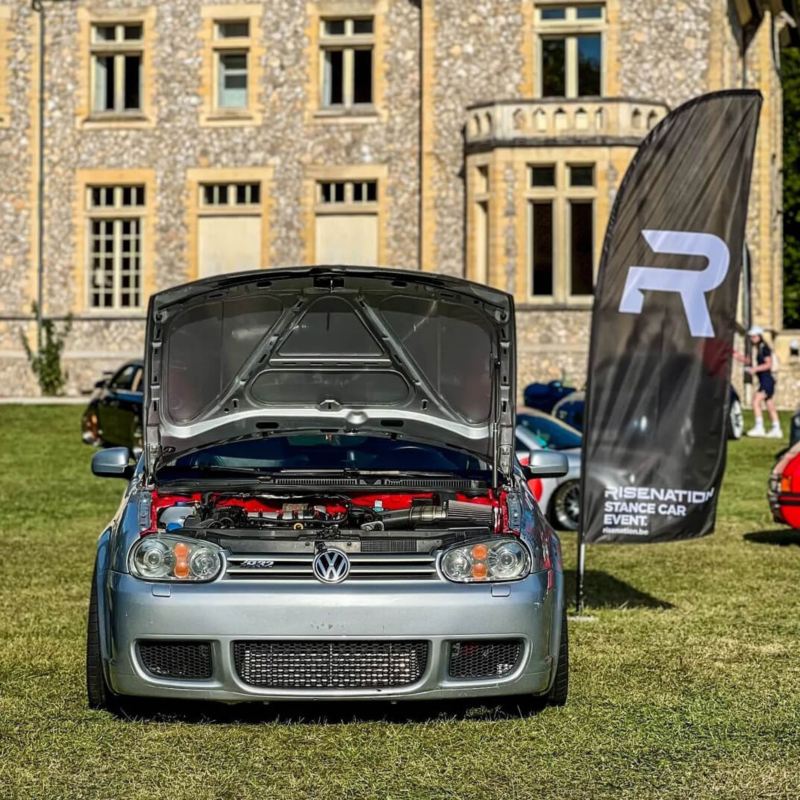 Golf 4 R32 grise customisée stationnée devant un château avec le capot ouvert.