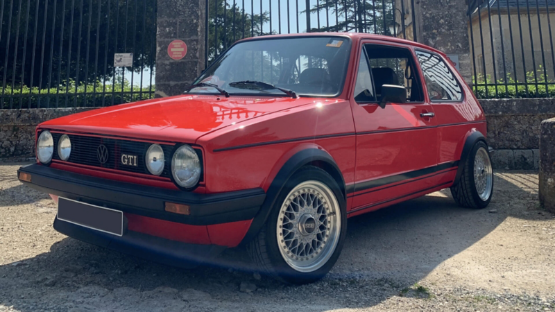 Golf GTI rouge customisée stationnée devant un portail.