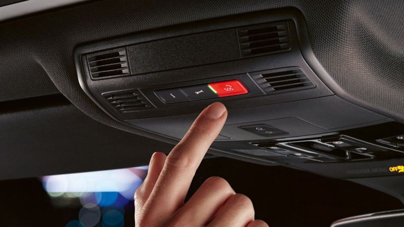 A woman pressing a button inside the car to activate the Emergency Call Service.