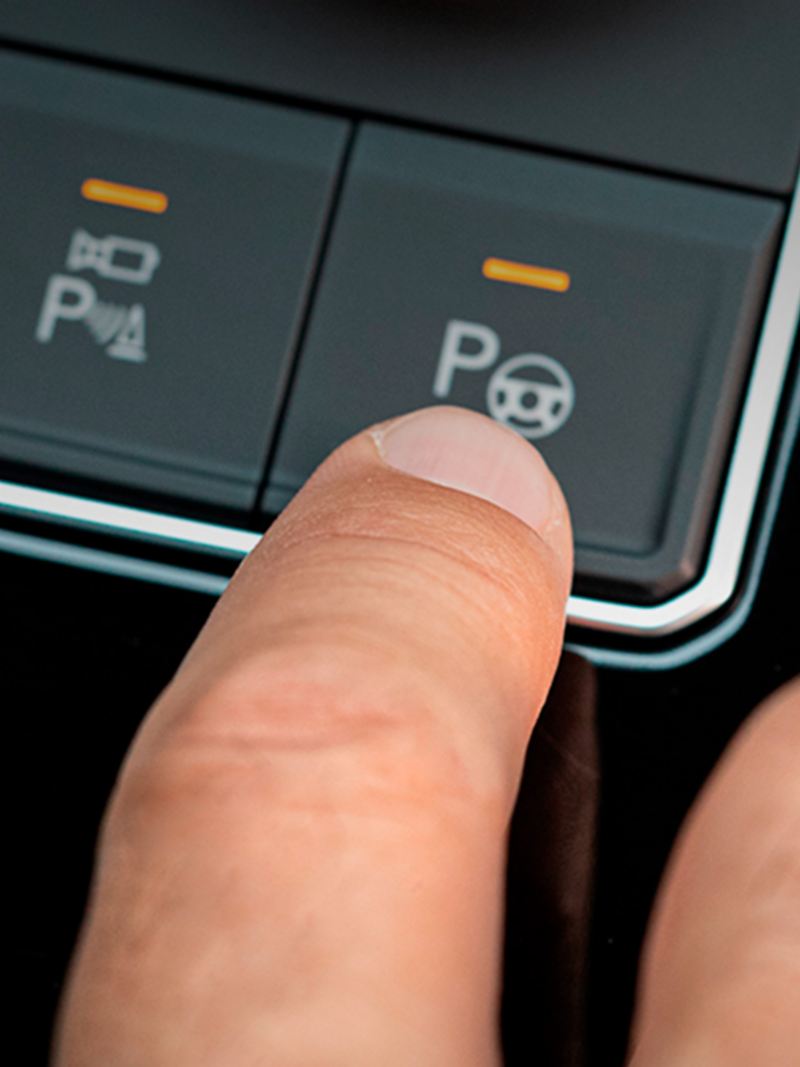 Que son sensores de reversa y Park Assist de Volkswagen - Dedo oprime botón de park assist en SUV.