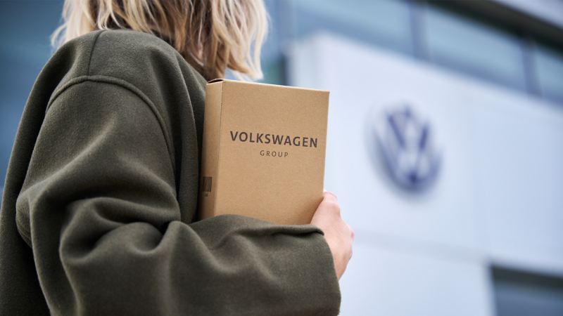 A woman holding a box of Volkswagen genuine parts