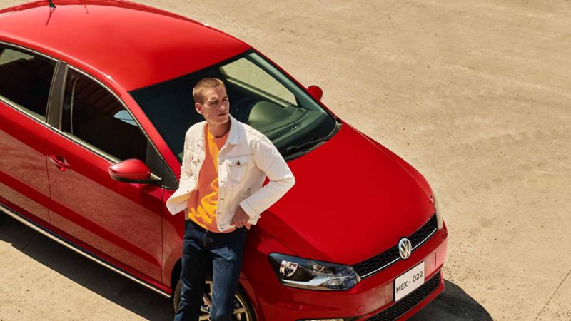 Autos compactos de Volkswagen - Polo 2021 en color rojo, con joven conductor recargado en cofre.