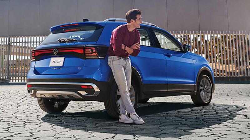 Taigun de Volkswagen en color azul, con hombre recargado cerca de cajuela.