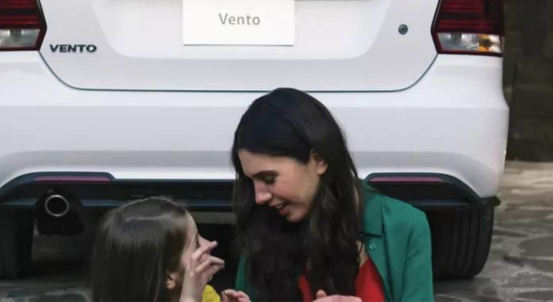Imagen de mamá e hija frente a la parte trasera de un vehículo vento