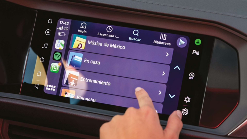 Dedo de pasajero toca la pantalla táctil de un vehículo Volkswagen. 