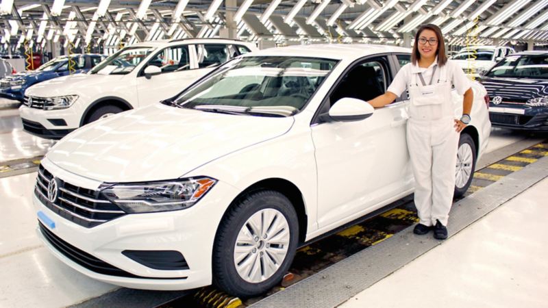 Mujer trabajadora con Jetta blanco en planta VW