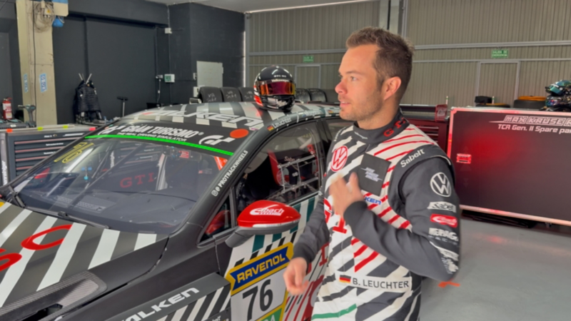 Benjamin «Benny» Leuchter en combinaison de course à côté d’une Volkswagen Golf GTI TCR dans le garage.