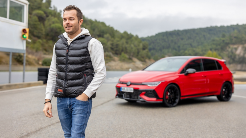 Benjamin «Benny» Leuchter se tient sur un circuit devant une Volkswagen Golf GTI rouge.