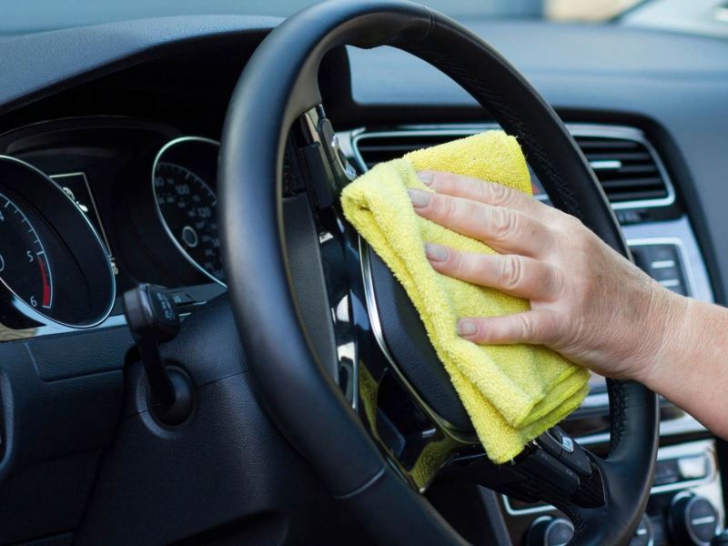 Imagen de muestra a una mujer limpiando el volante de su auto Volkswagen.