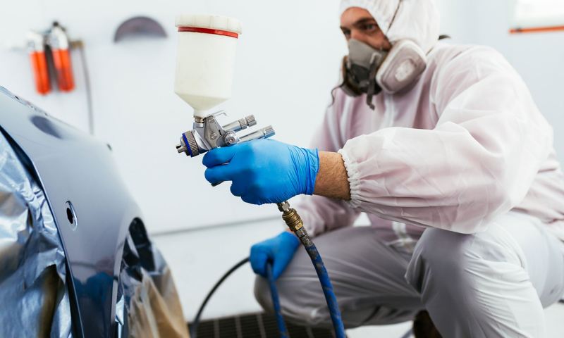 A Volkswagen repair expert spray painting a vehicle