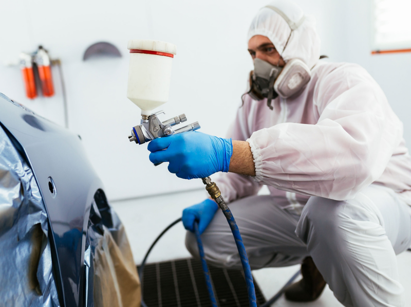 A Volkswagen repair expert spray painting a vehicle