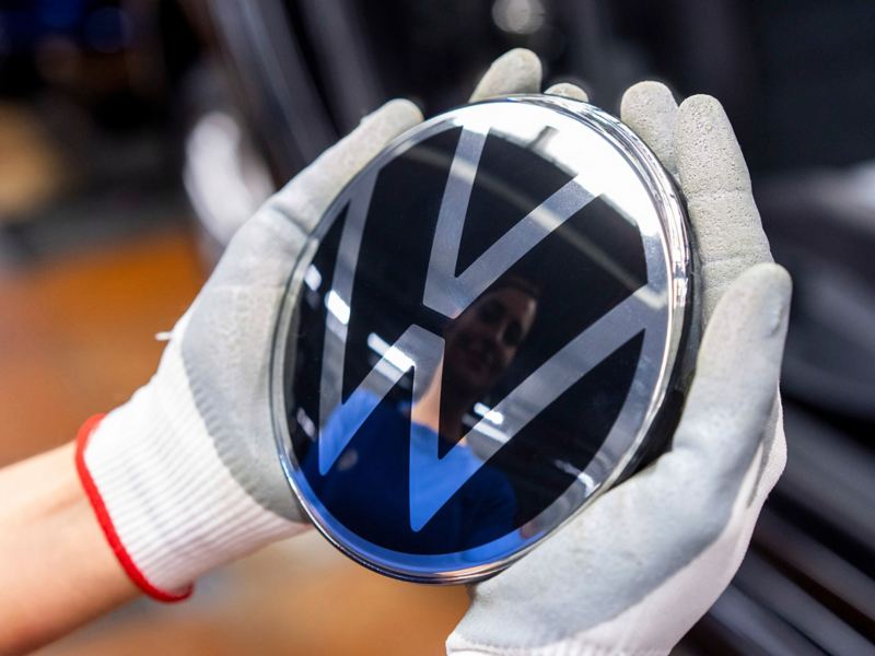 VW Logo liegt in den Händen eines Mitarbeiters