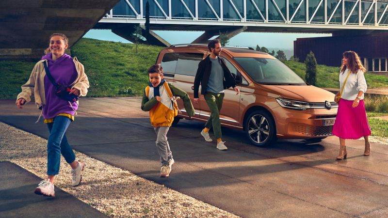 The new Volkswagen Caddy in front of a modern building.