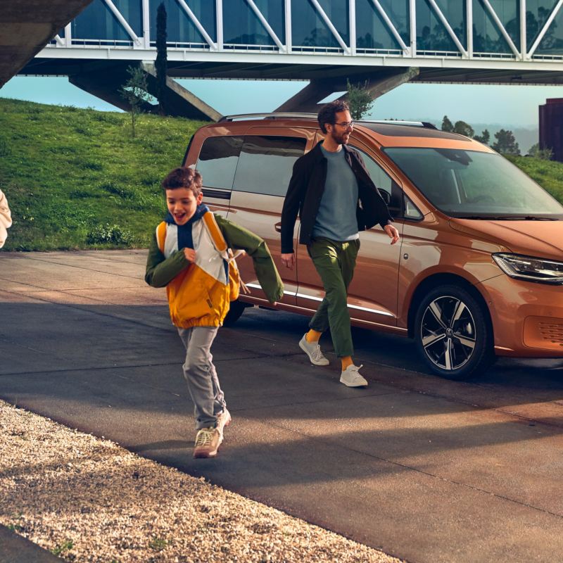 Familj framför en orange VW Caddy personbil