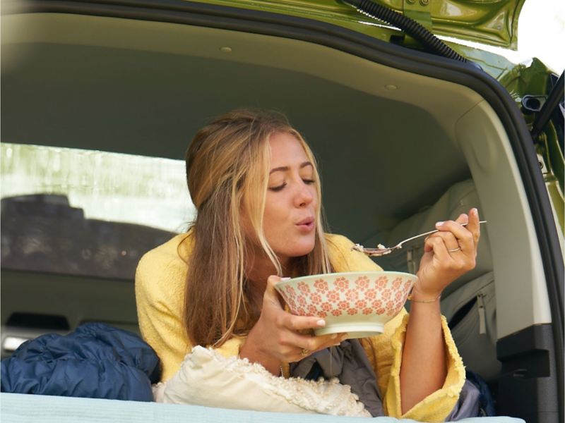 Kvinna äter en måltid i en Caddy California husbil