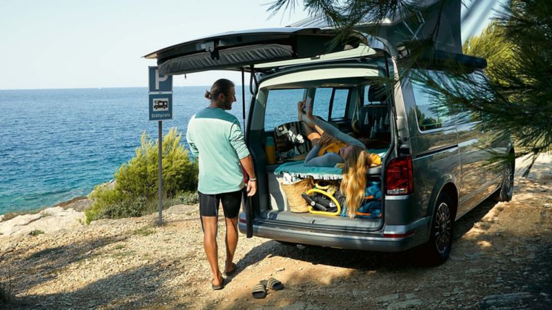 Man står bakom en VW California campingbil