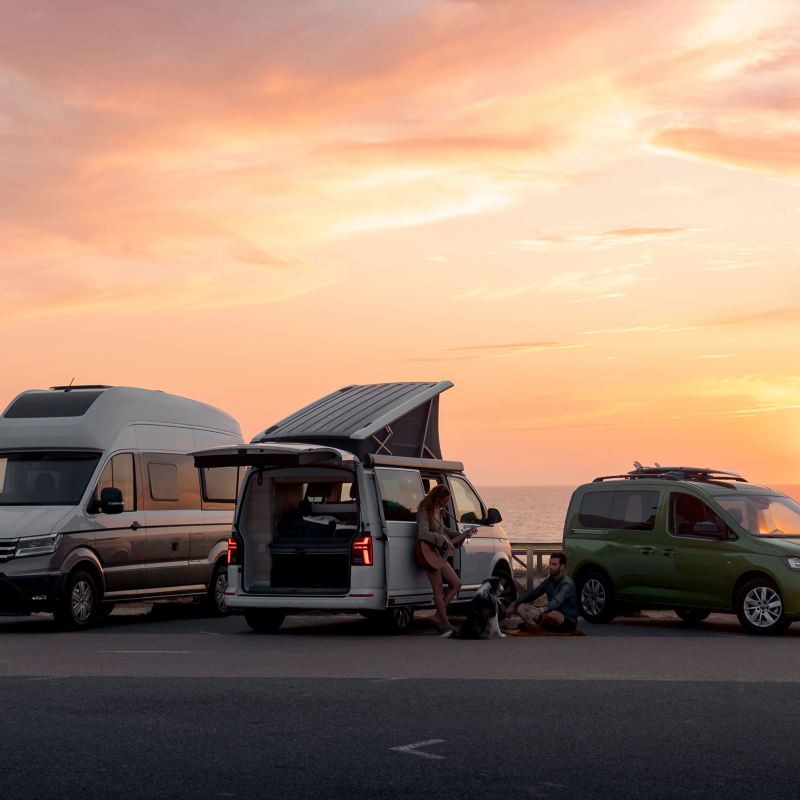 VW California 6.1, VW Caddy California och VW Grand California uppställda på en strand i solnedgång