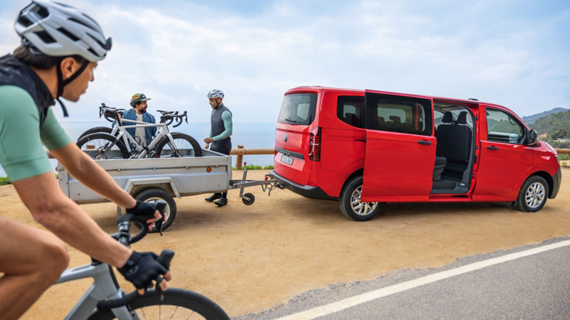 Cyklister står vid en VW Caravelle med släp