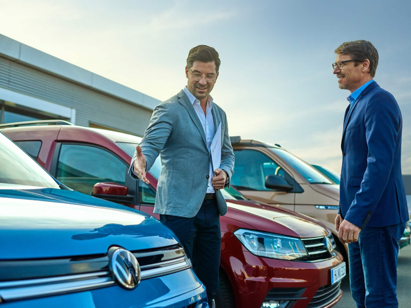 Ein Verkäufer zeigt einem Kunden ein Volkswagen Nutzfahrzeug.