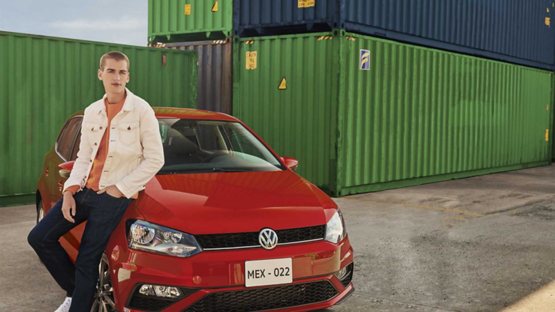 Polo 2021 Comfortline en color rojo, estacionado cerca de contenedores. 