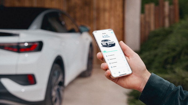 Un personne utilise VW Connect sur son smartphone devant son ID.5 blanc.