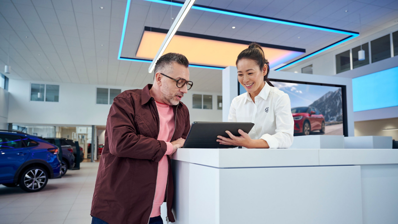 Cliente de Volkswagen revisa detalles en una carpeta mostrada por agente VW. 