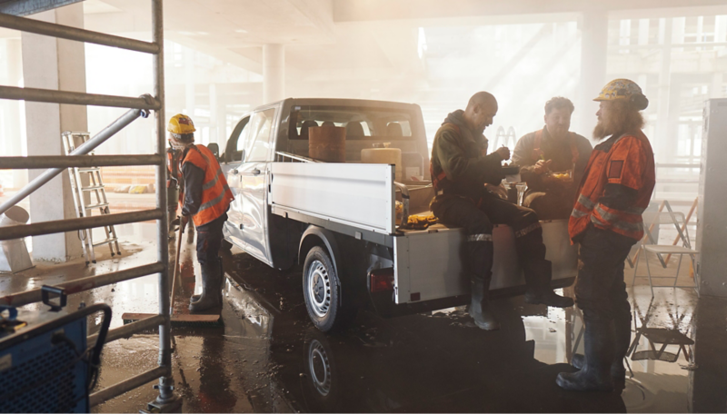 Mehrere Bauarbeiter pausieren um einen VW Crafter Pritschenwagen.