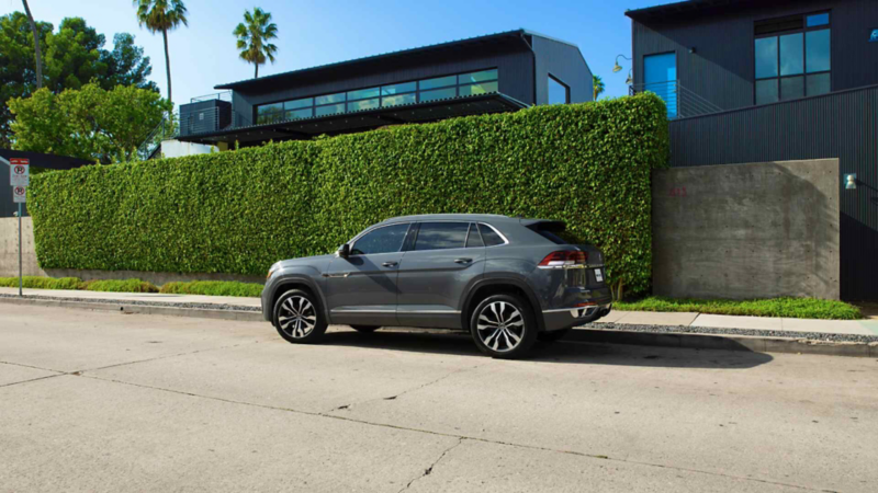 SUV Cross Sport VW en color gris, estacionada a las afueras de una casa con pared cubierta de vegetación. 