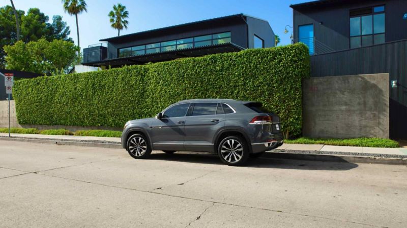 SUV Cross Sport VW en color gris, estacionada a las afueras de una casa con pared cubierta de vegetación.