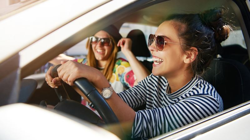 zwei Frauen sitzen im Auto und lachen