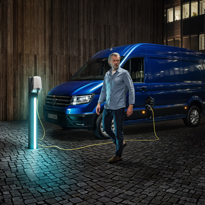 Niebieski Volkswagen e-Crafter z wysokim dachem podczas ładowania.