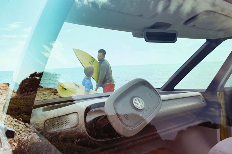 Vater und Sohn sind mit dem VW ID. BUZZ an einer steinigen Küste unterwegs und gehen surfen.