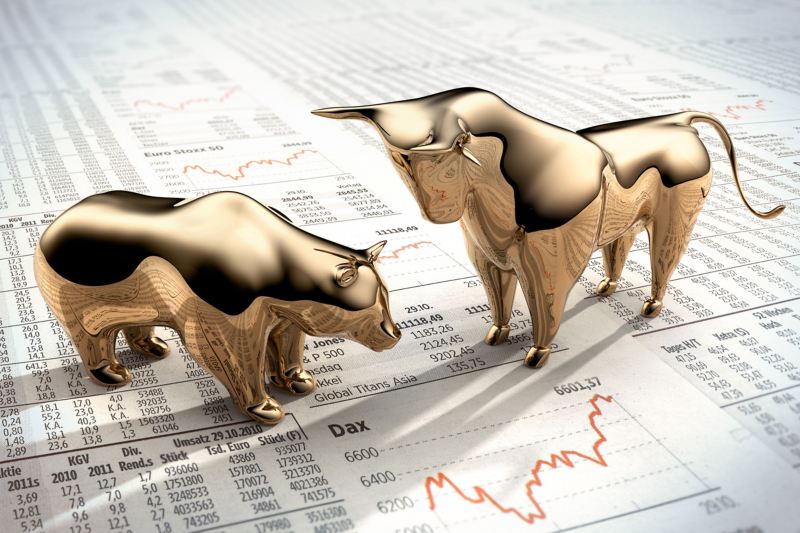 Goldene Figuren von Bär und Bulle stehen auf einer Zeitung mit Aktienkursen