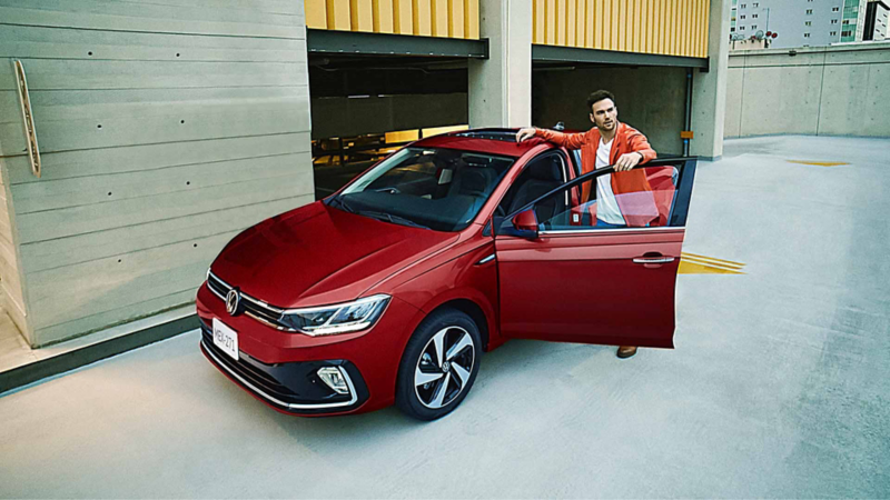 Virtus 2026 en color rojo, con joven conductor a punto de abordar el auto sedán de Volkswagen. 