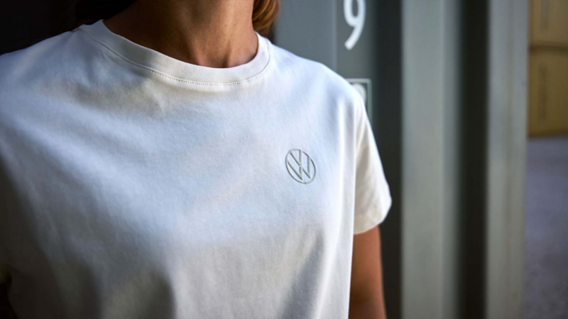 Persona con camiseta blanca y logotipo Volkswagen bordado en el pecho.