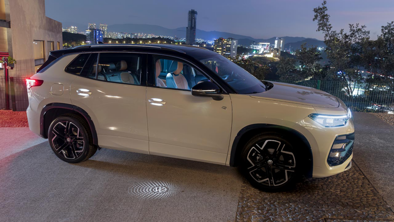 VW Tiguan 2025. Vista lateral de camioneta SUV para 5 pasajeros, con luces de piso que muestran logo VW.