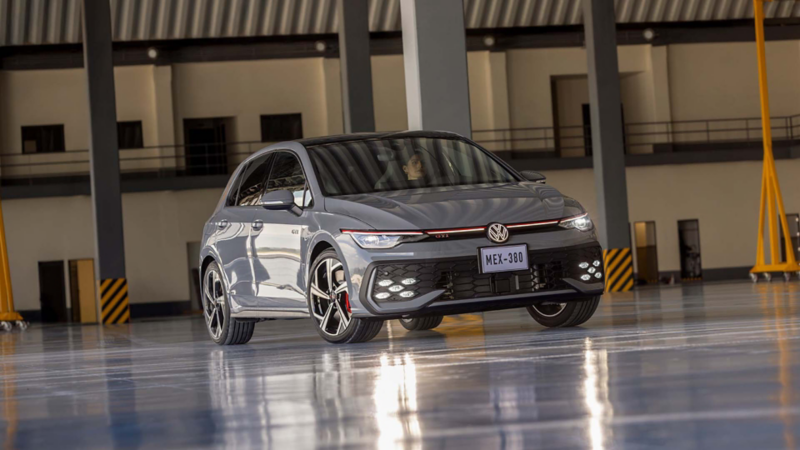 Carro deportivo de Volkswagen Golf GTI en color exterior gris con luces delanteras encendidas. 