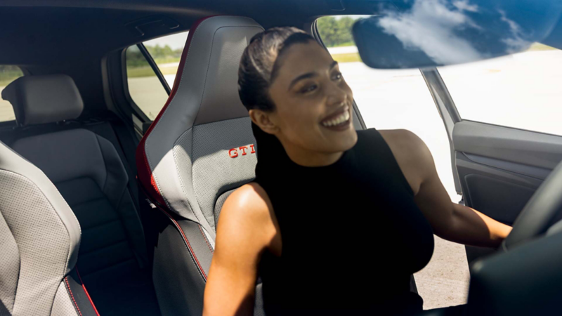 Mujer que sonríe entra a un carro deportivo de Volkswagen.