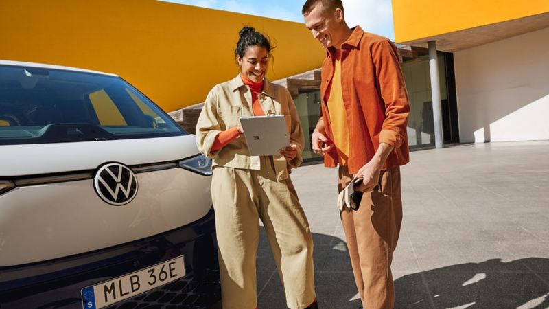 Två personer framför en VW ID. Buzz
