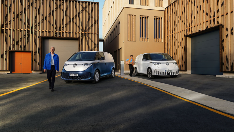 En man står framför en ID. Buzz Cargo medan en annan man står vid laddstolpe och laddar en VW ID. Buzz Cargo