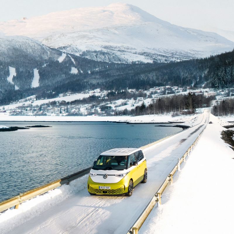 En tvåfärgad gul-vit VW ID. Buzz elbil i fjällen på vintern.