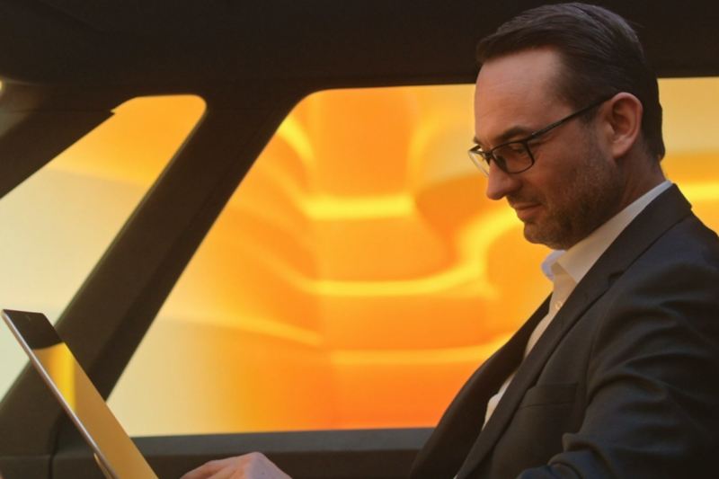 Christian Senger siede in VW ID. Buzz con un laptop.