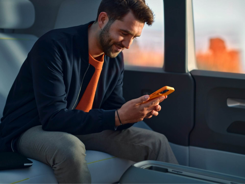 Nono Konopka siede a bordo del Volkswagen ID. Buzz con lo smartphone in mano.