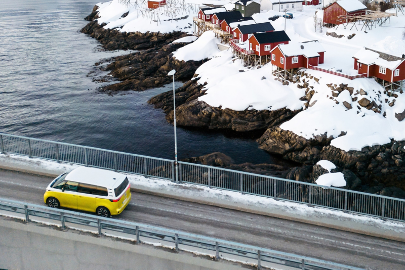 Der VW ID. Buzz an einer verschneiten Küste fährt über eine Brücke.