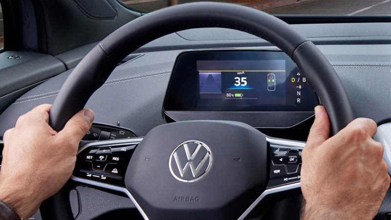 Conductor toma el volante de ID.4, mientras el digital cockpit muestra kilometraje y capacidad de batería. 