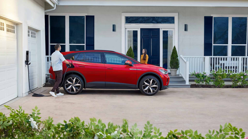 Hombre conecta cable a un Volkswagen ID.4 para cargarlo desde su casa.