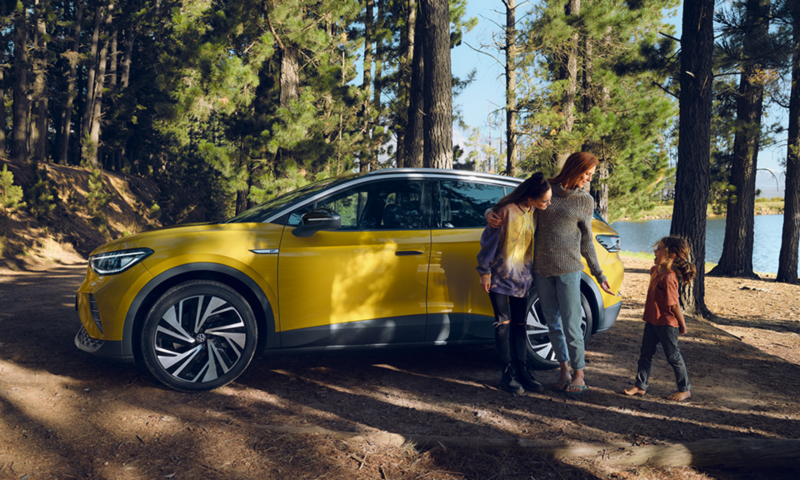 ID.4 is standing in a forest with a woman and two children.