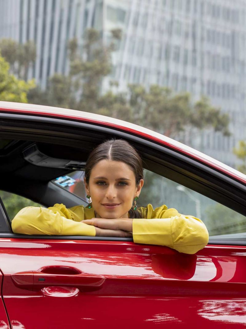 Mujer vestida con blusa amarilla sobresale de la ventana de copiloto de Jetta 2024