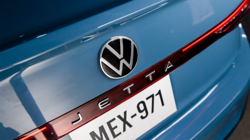 Emblema Jetta y logo VW en la cajuela de auto sedán en color azul.