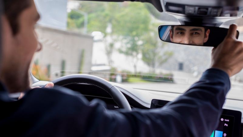 Conductor de Jetta 2025 manipula el espejo retrovisor en el interior del auto. 